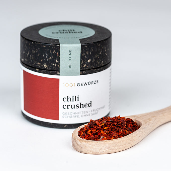 Chili Flocken ohne Saat in Dose, Gewürz sichtbar auf Holzlöffel